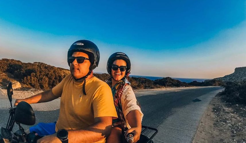 Leo e Pri de moto por uma estrada litorânea ao entardecer
